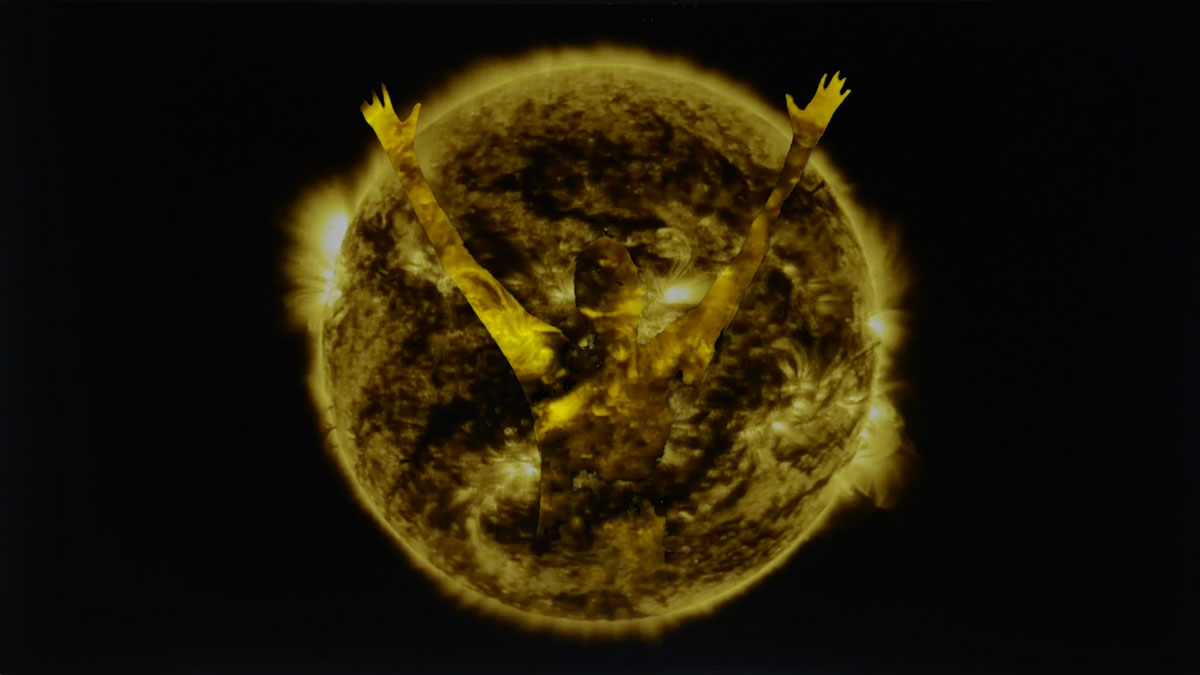 video still image of a human form bursting from the sun